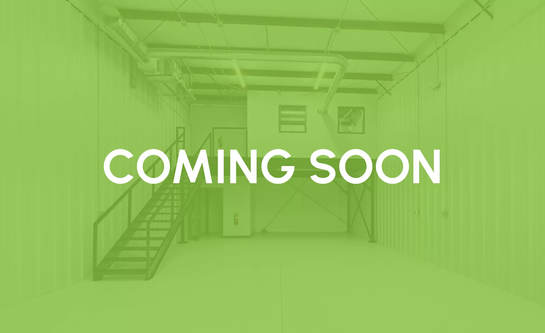 Green-tinted warehouse interior with mezzanine stairs and exposed pipes, COMING SOON overlay.