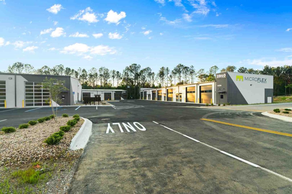 MicroFlex facility exterior with a row of roll-up doors and a parking lot under a blue sky.